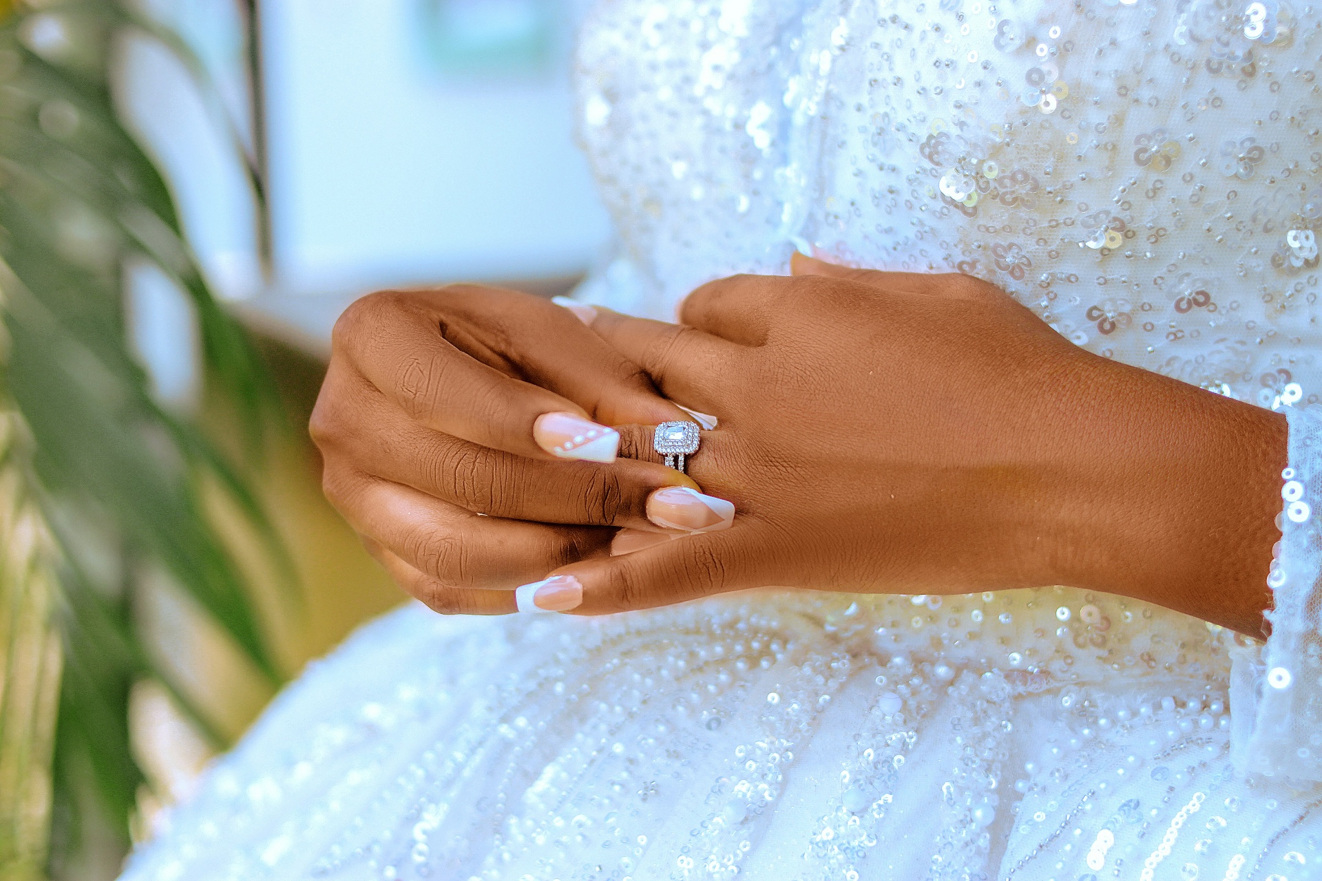 Bride's hands resting on a sequinned gown with her ring