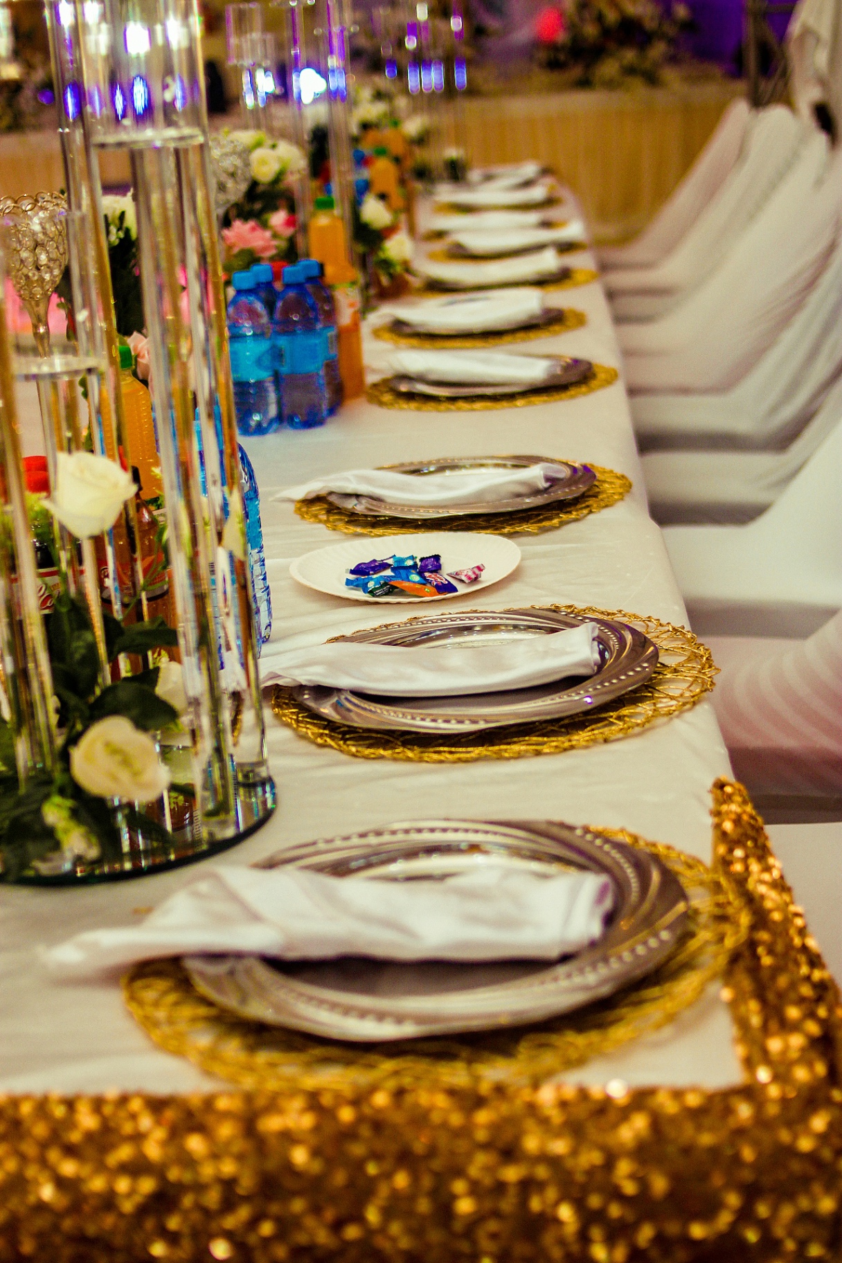 Long banquet table with gold chargers and crystal centrepieces