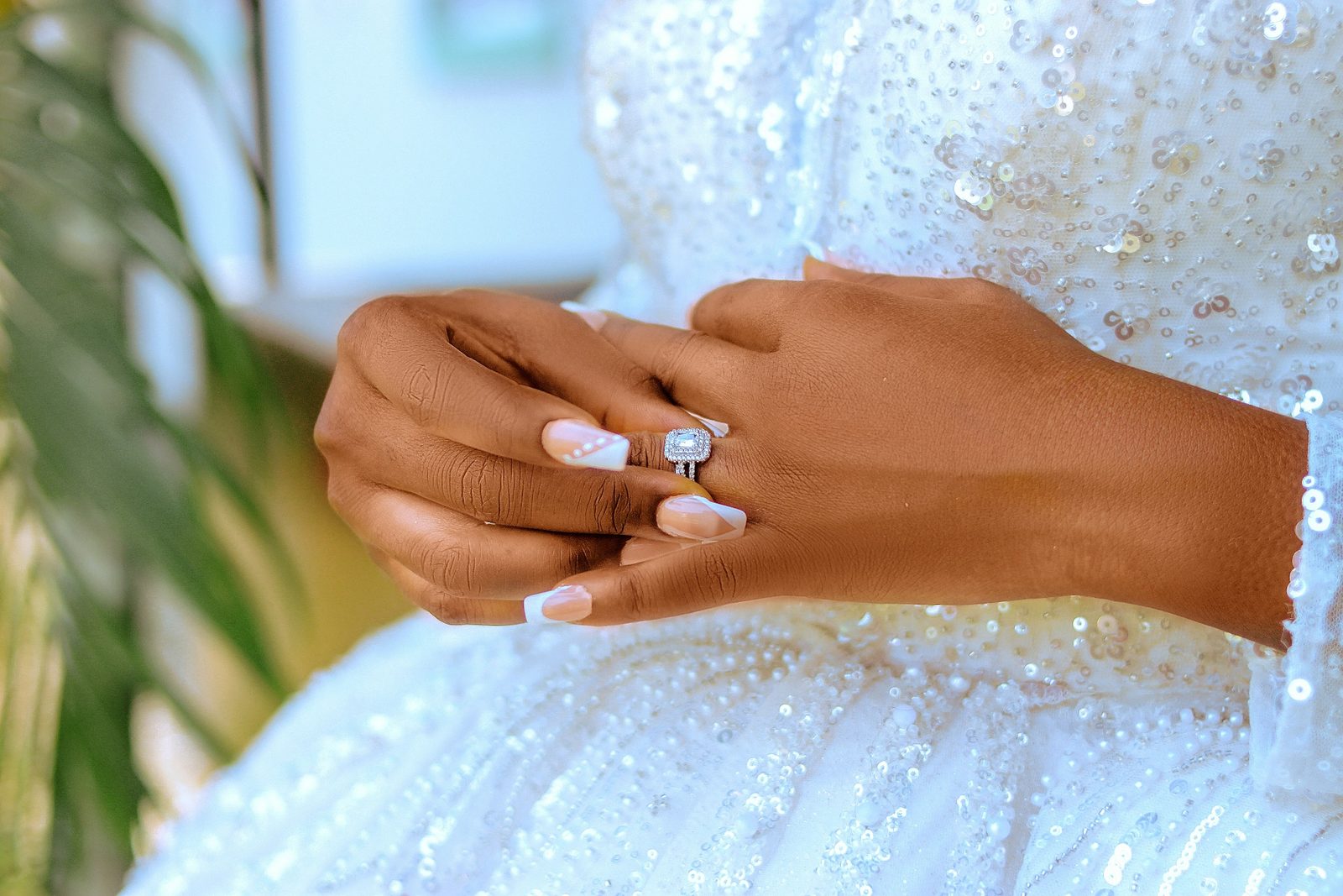 Bride's hands resting on a sequinned gown with her ring